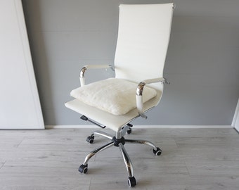 May include: White office chair with a white faux fur cushion. The chair has a chrome base and five wheels.