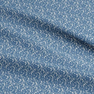 May include: Close-up of a blue fabric with a white floral pattern. The fabric has a soft, textured appearance, with the white design resembling delicate flowers or leaves. The overall aesthetic is a blend of nature and textile design.