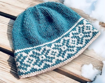 May include: A teal blue knitted hat with a white and teal geometric pattern around the brim.