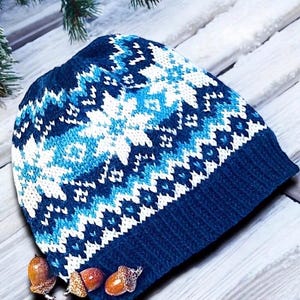 Può includere: Cappello invernale di lana blu con un motivo a fiocco di neve bianco e blu.