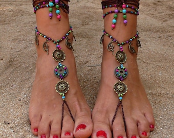 May include: A pair of brown foot jewellery with colourful beads and metal charms. The jewellery features a series of circular charms with colourful beads and a crescent moon design.