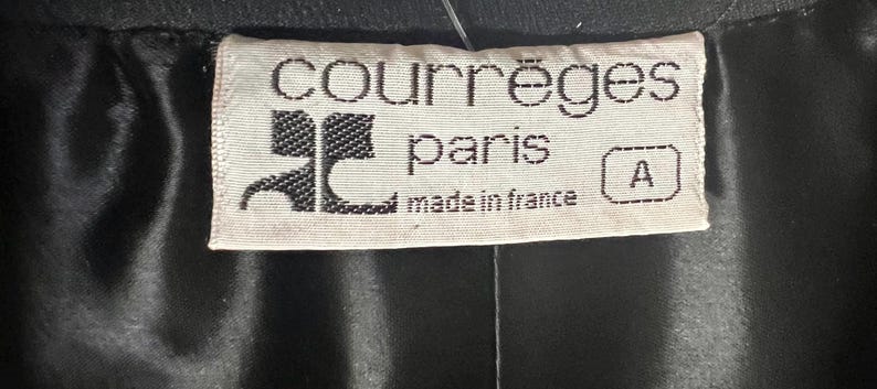May include: White label with black text that reads "Courr&egrave;ges Paris made in France" and a black logo with the letter "C". The label also has a small white tag with the letter "A" in black.