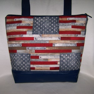 Pu&ograve; includere: Una borsa tote con un design patriottico. La borsa presenta un motivo che ricorda la bandiera americana, con strisce rosse e bianche e un campo blu di stelle. Il fondo della borsa &egrave; blu navy tinta unita e ha manici blu navy.