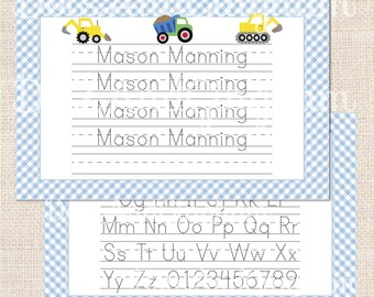 Può includere: Un tovaglietta laminata a quadretti blu e bianchi con un lato anteriore che presenta un'area di pratica dei nomi con il nome "Mason Manning" scritto quattro volte e tre illustrazioni di veicoli da costruzione. Il lato posteriore presenta l'alfabeto e i numeri in un motivo a quadretti blu e bianchi.
