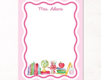 Può includere: Blocco note rosa con un bordo a festoni e il testo "Mrs. Adams" in alto. La parte inferiore del blocco note presenta un'illustrazione ad acquerello di materiale scolastico, tra cui libri, un mappamondo, matite, una mela, un righello e colla.