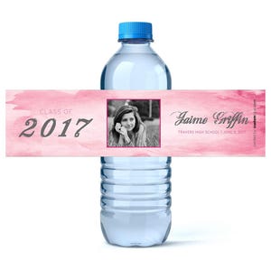 Puede incluir: Etiqueta de botella de agua para una fiesta de graduaci&oacute;n en acuarela rosa y blanca con una foto de una chica, el texto "Clase de 2017" y el nombre "Jaime Griffin" con la escuela y la fecha.
