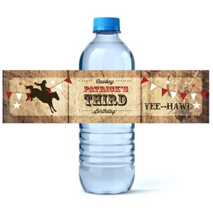 Pu&ograve; includere: Una bottiglia d'acqua con un'etichetta personalizzata per un terzo compleanno. L'etichetta ha un tema da cowboy con una silhouette di un cowboy a cavallo, gagliardetti rossi e bianchi e il testo "Cowboy Patrick's Third Birthday" e "Yee-Haw!"