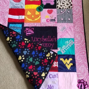 Pu&ograve; includere: Una trapunta trapuntata rosa e bianca con un retro in pile nero. La trapunta &egrave; realizzata con diversi tessuti, tra cui magliette con diversi disegni e frasi. Alcune delle frasi includono "Wonder Woman", "Rispondo solo alla principessa", "Little Miss Attitude" e "Lucybelle's Tommy".
