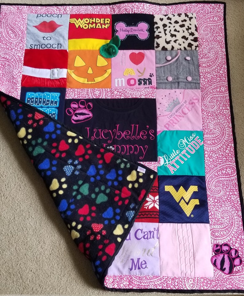 Pu&ograve; includere: Una trapunta trapuntata rosa e bianca con un retro in pile nero. La trapunta &egrave; realizzata con diversi tessuti, tra cui magliette con diversi disegni e frasi. Alcune delle frasi includono "Wonder Woman", "Rispondo solo alla principessa", "Little Miss Attitude" e "Lucybelle's Tommy".