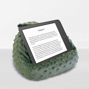 May include: A green, textured reading pillow with a tablet displaying text from "Chapter 1." The pillow is designed to prop up a tablet or e-reader. The text on the screen is about William Brewster, organizer of the Pilgrim Church.