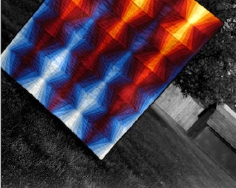 以下が含まれることがあります： 赤、オレンジ、黄色、青、白の色の幾何学模様のキルト。キルトの名前は「Fire & Ice」で、13 Spoolsのパターンです。