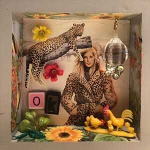 May include: A framed collage with a leopard print theme. The collage includes a leopard print coat, a leopard, a crystal prism, and the letters "OK" in pink and black.