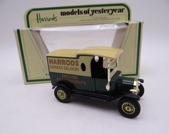Puede incluir: Un modelo de juguete de furgoneta Harrods Express Delivery en verde oscuro y beige. El juguete tiene ruedas negras con detalles dorados y el logotipo de Harrods. El embalaje es visible en el fondo.