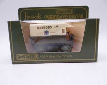 Puede incluir: Un modelo de juguete de camión de reparto vintage Harrods Ltd. de la colección Matchbox Models of Yesteryear. El camión es blanco y verde con las palabras "Harrods Ltd." impresas en el lateral. El camión está sobre una caja de cartón verde y dorada con las palabras "Matchbox" e "Y29 Walker Electric Van" impresas en ella.