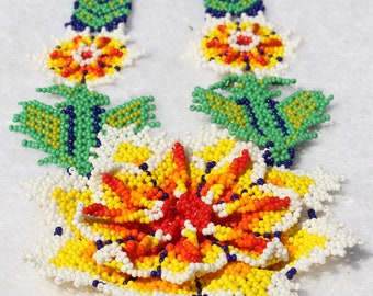 May include: A colorful beaded necklace with a large flower design in the center. The flower is made of white, yellow, orange, and red beads. The necklace has a fringe of beads in the same colors.