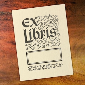 Bookplate with &quot;Ex Libris&quot; inscription in bold, gothic-style lettering, surrounded by intricate, hand-drawn floral and vine embellishments.