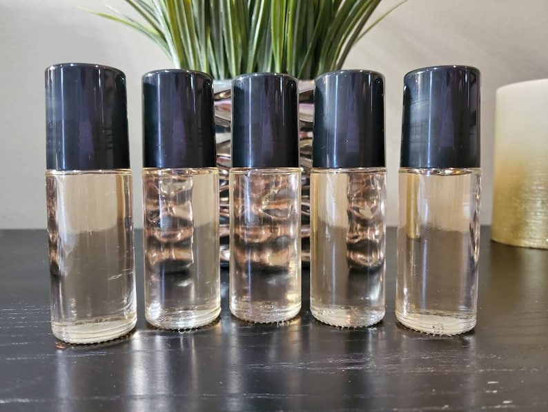 Puede incluir: Cinco botellas de vidrio transparente con tapones negros. Las botellas est&aacute;n llenas de un l&iacute;quido marr&oacute;n claro.