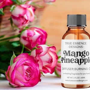 Könnte beinhalten: Eine braune Glasflasche mit schwarzem Verschluss und einem weißen Etikett mit der Aufschrift "TRUE ESSENCE -DESIGNS- Mango Pineapple DIFFUSER|BURNING OIL a refreshing fragrance for your home NET WT. 2 FLOZ | 60ML www.trueessencedesigns.com".