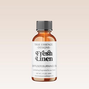 Könnte beinhalten: Eine braune Glasflasche mit schwarzem Verschluss und einem weißen Etikett. Das Etikett lautet "TRUE ESSENCE -DESIGNS- Fresh Linen DIFFUSER|BURNING OIL a refreshing fragrance for your home NET WT. 2 FLOZ | 60ML www.trueessencedesigns.com"