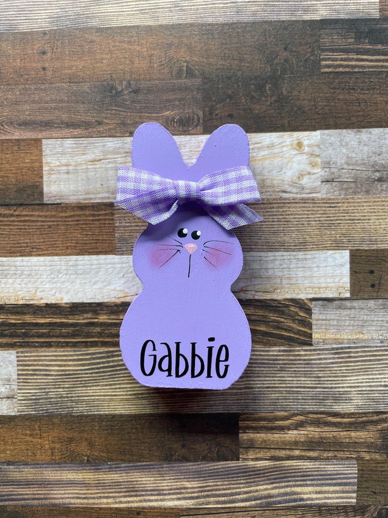 K&ouml;nnte beinhalten: Drei Keramikbecher mit gesprenkelter, cremefarbener Glasur. Jeder Becher zeigt ein handgemaltes Blumendesign in Blau-, Gr&uuml;n- und Gelbt&ouml;nen. Die Becher haben eine einfache, abgerundete Form und einen Griff.