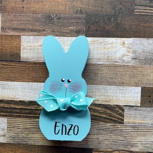 K&ouml;nnte beinhalten: Eine wei&szlig;e Keramik-Tasse mit schwarzem Henkel und dem Text "But First, Coffee" in fetter, schwarzer Schrift. Die Tasse steht vor einem verschwommenen Hintergrund. Die Tasse ist etwa 10 cm hoch.