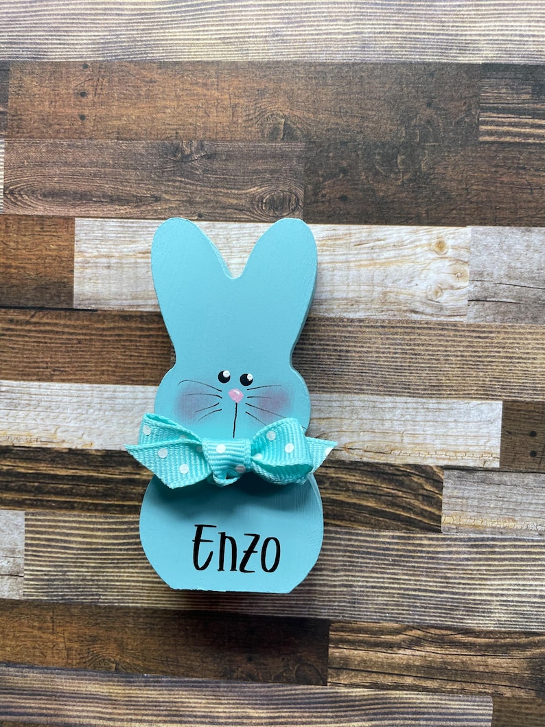 K&ouml;nnte beinhalten: Eine wei&szlig;e Keramik-Tasse mit schwarzem Henkel und dem Text "But First, Coffee" in fetter, schwarzer Schrift. Die Tasse steht vor einem verschwommenen Hintergrund. Die Tasse ist etwa 10 cm hoch.