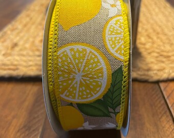 May include: A roll of yellow and brown ribbon with a lemon print. The ribbon has a white background with yellow lemons and green leaves.