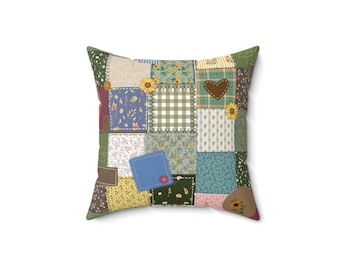 Puede incluir: Cojín cuadrado con diseño de patchwork. El cojín presenta varios cuadrados de tela en tonos verdes, azules, amarillos y marrones, con estampados florales y de cuadros. Se ven un corazón marrón y detalles de girasoles.