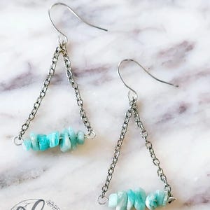 May include: A pair of silver triangle earrings with a cluster of light blue aquamarine stones.