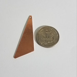 May include: A copper triangle pendant with a hole at the top. The pendant is about the size of a US quarter.