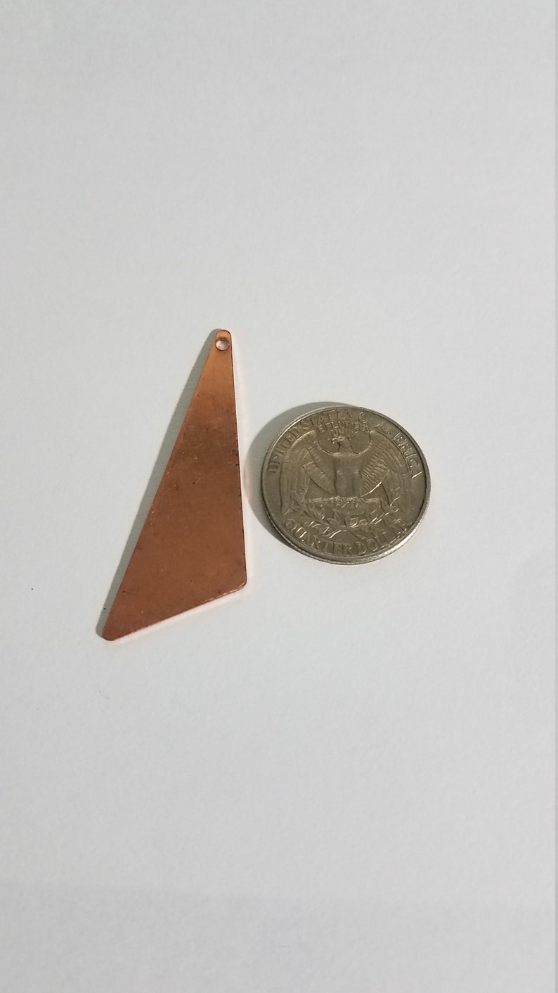 May include: A copper triangle pendant with a hole at the top. The pendant is about the size of a US quarter.