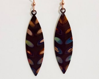 May include: A pair of dangle earrings with a dark brown, leaf-shaped design. The leaves have a multi-colored pattern with shades of green, blue, and pink. The earrings are made of metal and have a rose gold finish.