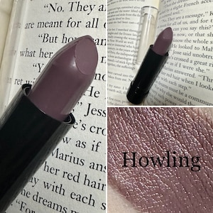 Puede incluir: Primer plano de una bala de lápiz labial morado oscuro en un tubo negro. El lápiz labial está etiquetado como "Howling".