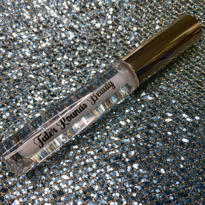 May include: A clear glass bottle with a silver cap and a white label that says "Tater Rounds Beauty".