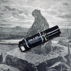 Puede incluir: Un frasco negro de roll-on con una etiqueta que dice "Reign in Hell" y enumera las notas de olor "Smoke, White Clove, Musk & Cedarwood". El frasco está sobre una ilustración en blanco y negro de una persona con una túnica con capucha.