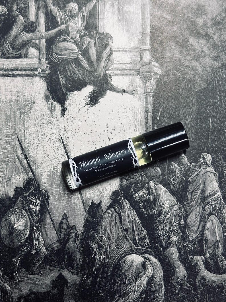 May include: A black roller bottle with a white label that reads "Midnight Whisper's Grave Dirt, Lily of the Valley & Elderflowers". The bottle is sitting on a black and white illustration of a scene with people and horses.