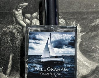 May include: A clear glass bottle of vegan perfume with a silver cap. The label reads "Will Graham Vegan Perfume" and features a sailboat on a body of water with a cloudy sky.