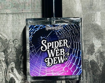 May include: A rectangular glass perfume bottle with a black cap. The label displays a spider web design with the words "Spider Web Dew" and "Vegan Perfume - 3.4 Oz". The background features an antique illustration.
