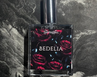 May include: A rectangular perfume bottle with a silver cap. The label features the text "Haunting Hues" and "BEDELIA" over a background of red roses. The bottle is set against a dark, gothic-style illustration.