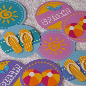 May include: Nine colorful round paper circles with various summer-themed designs. The designs include a sun, flip flops, beach balls, and the word "SPLASH!" in a blue, yellow, and pink color scheme.