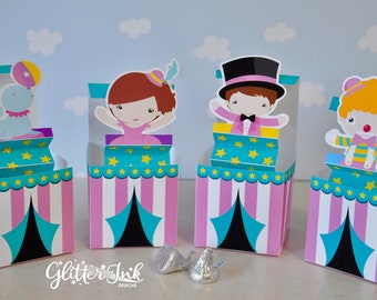May include: Four colorful favor boxes with circus themes. Each box features a different character: a clown, a magician, a ballerina, and a seal. The boxes are pink, white, and turquoise with yellow stars and a black tent.