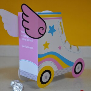 Peut inclure: Une carte en forme de patin &agrave; roulettes rose et blanche avec une aile rose sur le c&ocirc;t&eacute;. La carte porte un message qui dit "Merci pour mon succ&egrave;s en patinage et en roulade ! Avec amour, Luna xoxo".