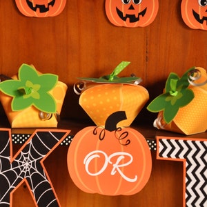 May include: A Halloween banner with orange and green pumpkin-shaped boxes, a black and white spiderweb letter "K", and an orange pumpkin with the word "OR" on it.