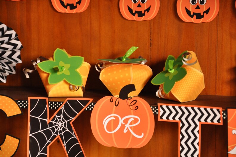 May include: A Halloween banner with orange and green pumpkin-shaped boxes, a black and white spiderweb letter "K", and an orange pumpkin with the word "OR" on it.