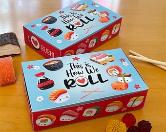 Puede incluir: Dos cajas de regalo rectangulares con temática de sushi, con fondo azul claro y borde rojo. Las cajas están decoradas con ilustraciones de sushi y la frase "This is How We ROLL". También se ven las palabras "I ❤️ SUSHI".