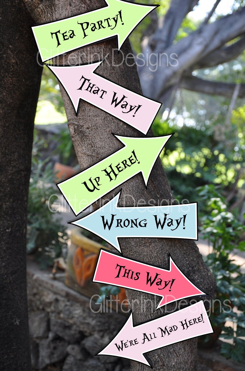 May include: Six colorful arrow signs with whimsical text attached to a tree trunk. The signs read "Tea Party!", "That Way!", "Up Here!", "Wrong Way!", "This Way!" and "We're All Mad Here!"