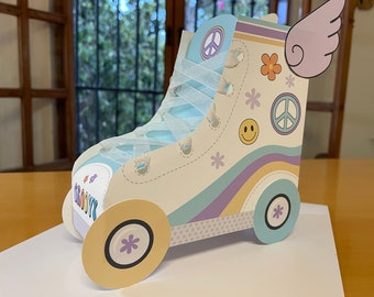 Può includere: Un pattino a rotelle di cartone bianco con un design blu e viola. Il pattino ha un segno di pace, una faccia sorridente e un fiore. Il pattino ha un nastro bianco legato intorno e un'ala bianca sul lato. Il pattino dice "Groovy" sul lato.