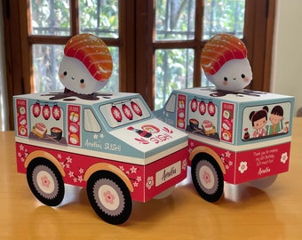 May include: Two red and white toy sushi trucks with a sushi character on top. The trucks have a blue and white interior with a window showing sushi and a soy sauce bottle. The trucks have the text "Amelia's Sushi" and "Sushi" on the side. The back of the truck has a thank you message and the name "Amelia".
