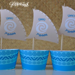 May include: Three blue and white cupcake wrappers with a brown sail on top. The sail has a white swirl design and the text "Liana's 7th Birthday".