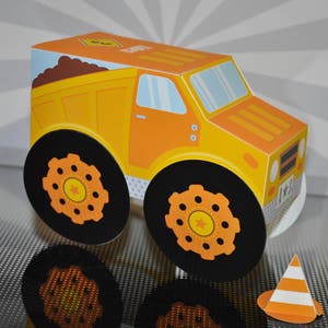 Pode incluir: Um caminhão de brinquedo amarelo com rodas pretas e uma caçamba de terra marrom. O caminhão tem uma estrela branca no lado e o número 8 no topo. O caminhão está sentado em uma superfície com padrão cinza e branco. Há um pequeno cone de trânsito laranja e branco no canto inferior direito da imagem.